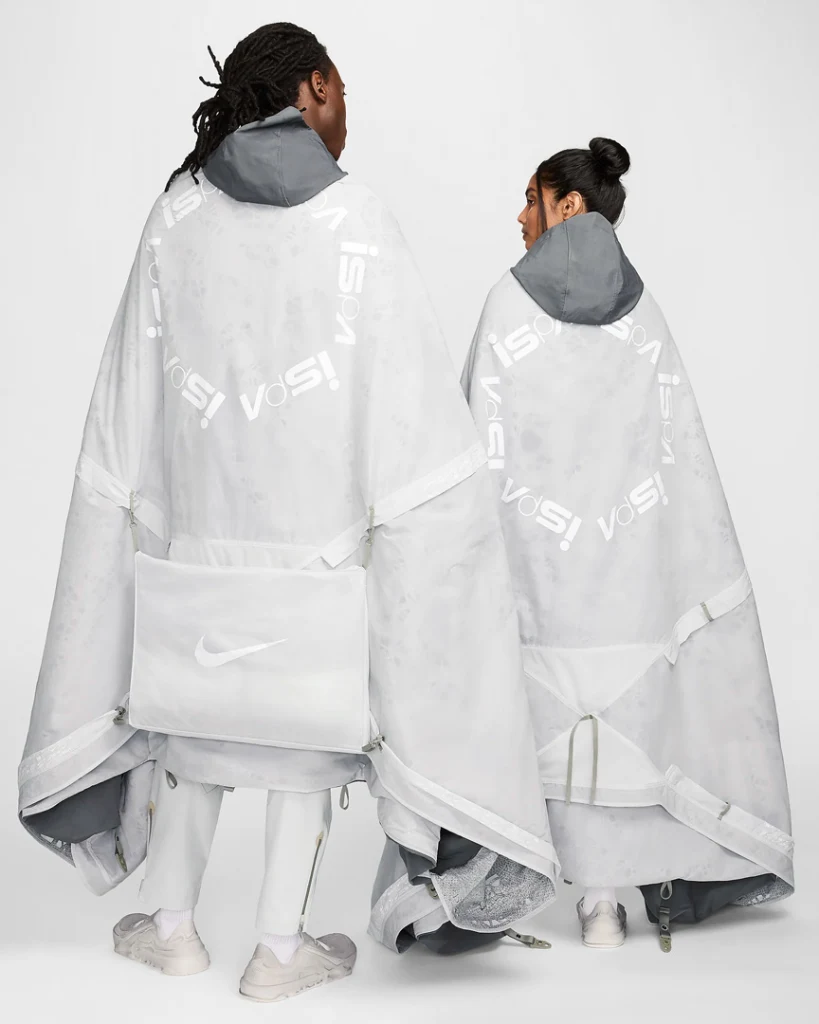 Two models with their backs to the camera wear the Nike ISPA Metamorph poncho.