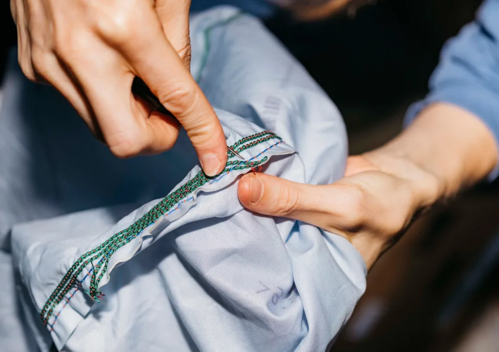 An up-close photo of hands stitching a bag seam together.