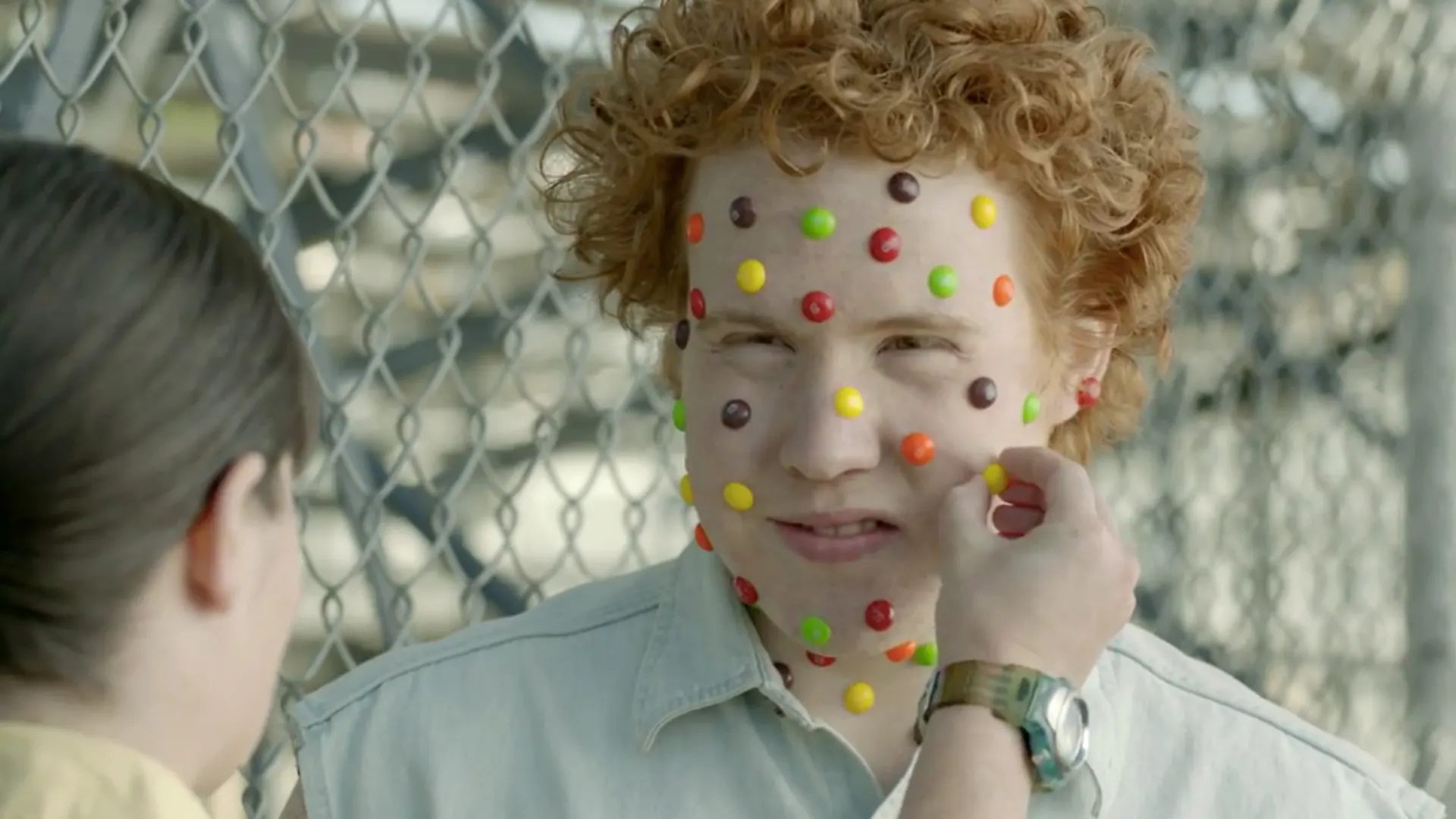 a frame from a Skittles advert where a boy has Skittles for acne