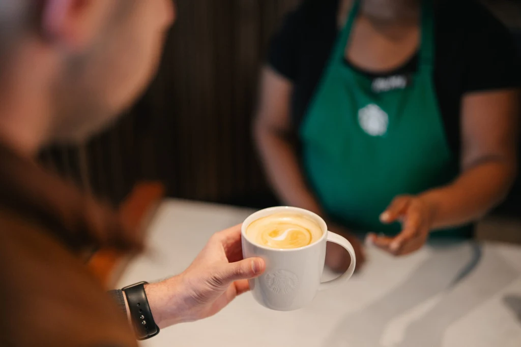 A customer is handed a ceramic mug, a new feature mentioned on Starbucks' earnings call.