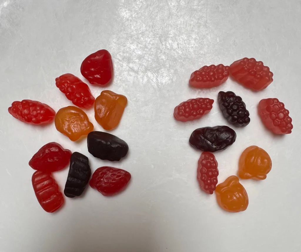 Two small groups of fruit snacks on a white table arranged side-by-side. The shapes of the individual pieces are unchanged, but the group of naturally dyed snacks on the right has are ever so slightly less saturated and vivid when compared directly to the artificially dyed group on the left. 