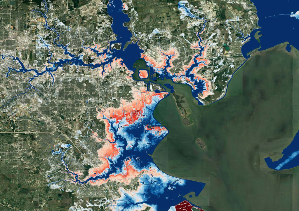 Satellite map of Houston with flood-risk zones overlaid. Red areas, often surrounding and extending beyond blue zones, highlight projected 2050 flood risks. The expansion is most prominent near bayous, rivers, and low-lying coastal areas, illustrating increased vulnerability due to climate change.