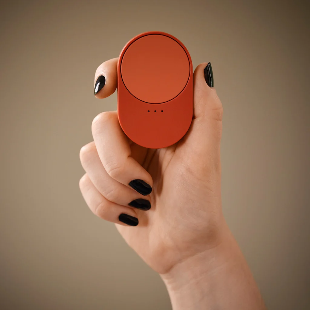 A hand holds a dark orange sensor within Ikea's smart home range.