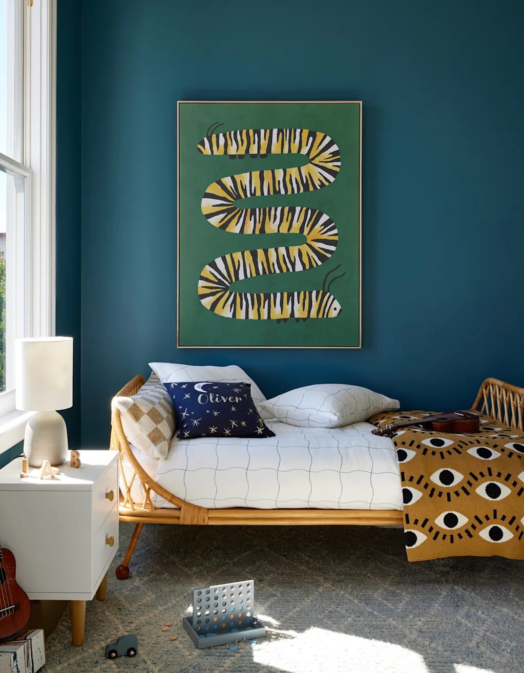 a large print portraying a caterpillar in a watercolor/papercut style on the wall of a childs bedroom