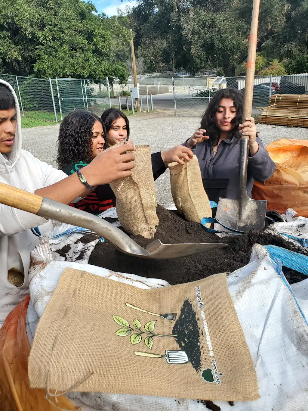 een groep jonge mensen laadt de aarde in kleine canvaszakken