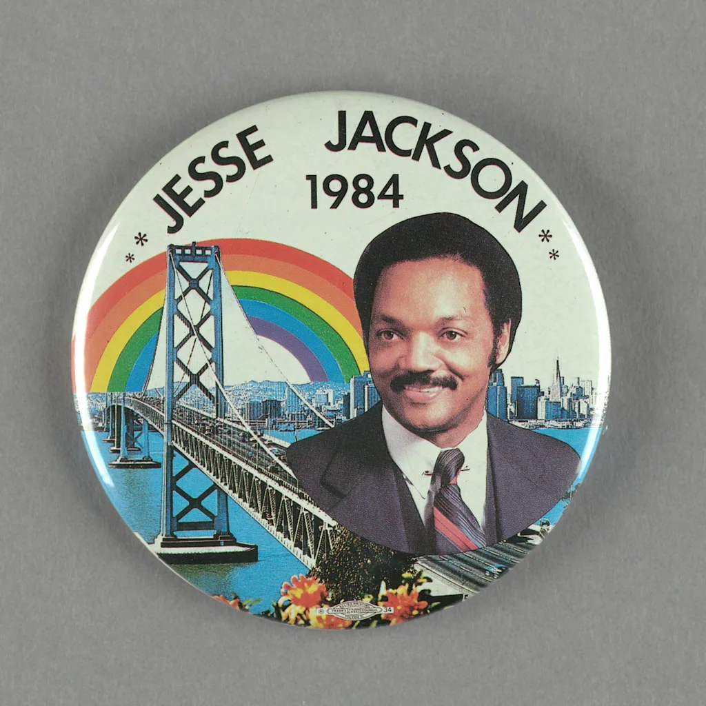 A button featuring a headshot of the politician over a bridge, city skyline, and rainbow reads: "Jesse Jackson 1984".