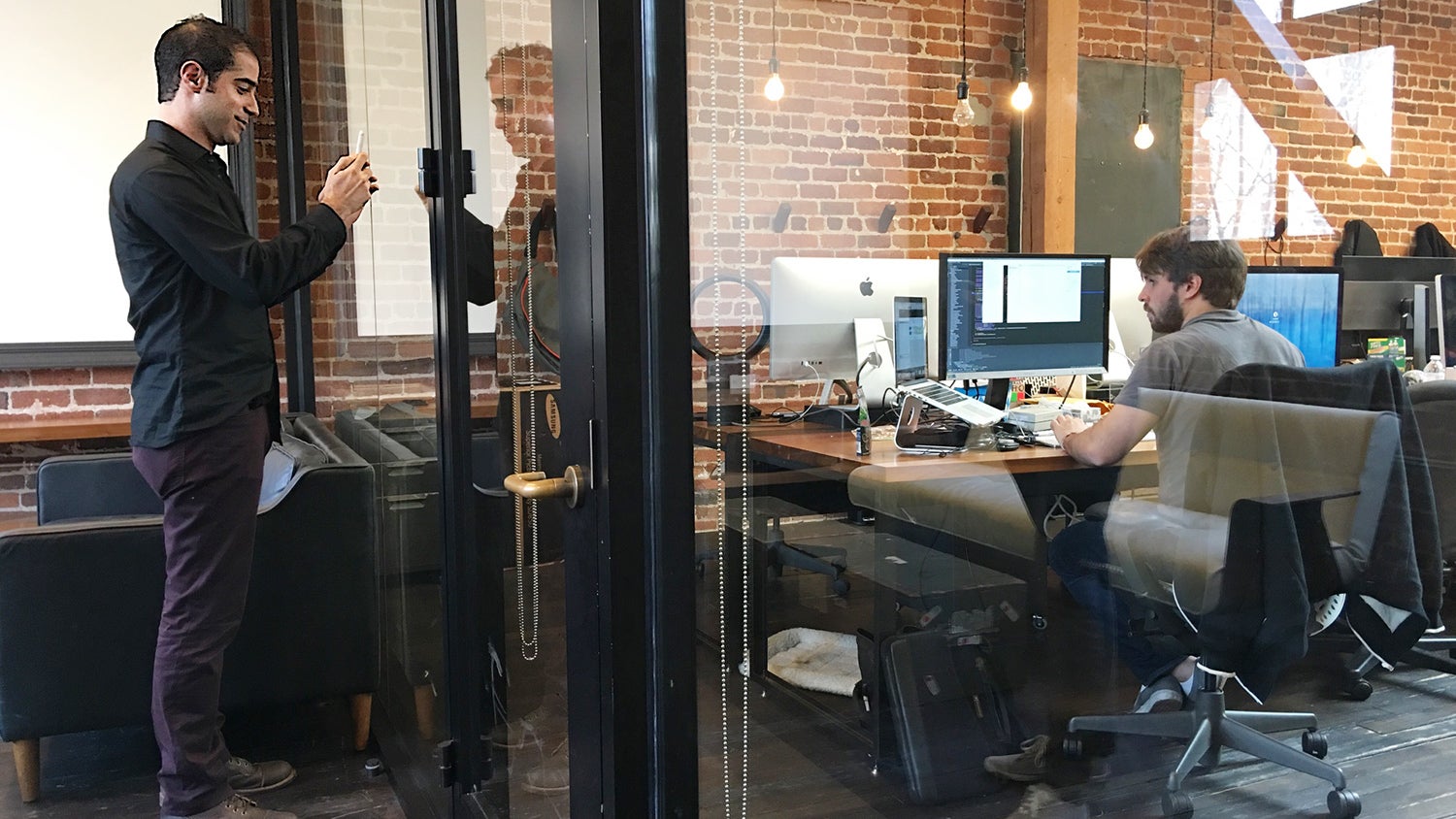 Kayvon Beykpour filming with a phone outside a glass-walled office